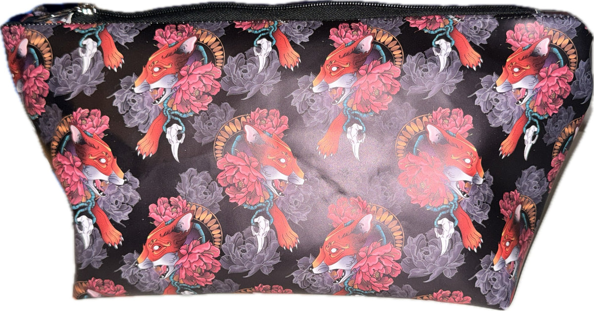 Black makeup bag printed with red tattoo-style foxes, pink and grey peonies, and bird skulls